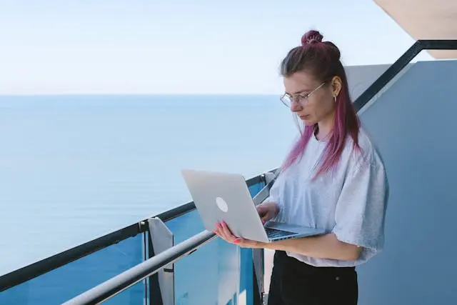 mujer con una laptops en un balcon frente al mar