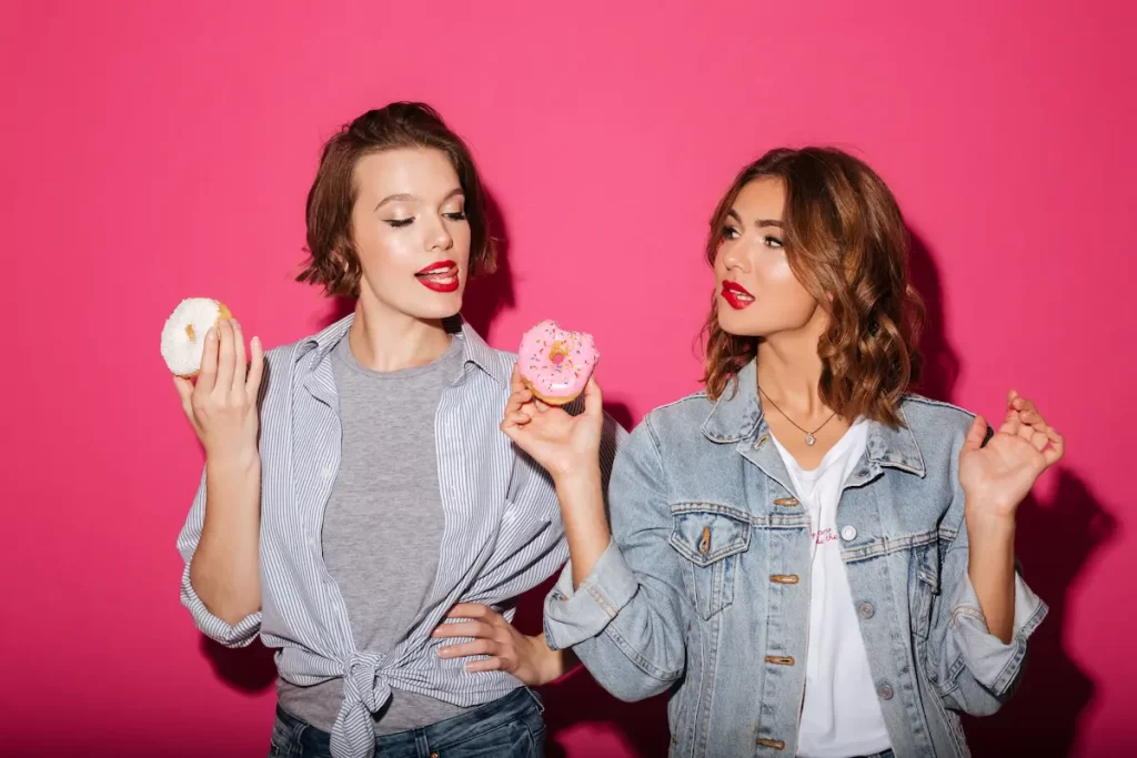 Hermosas dos amigas comiendo donas