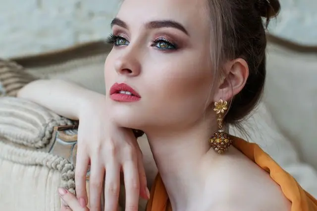 mujer maquillada con aretes colgantes