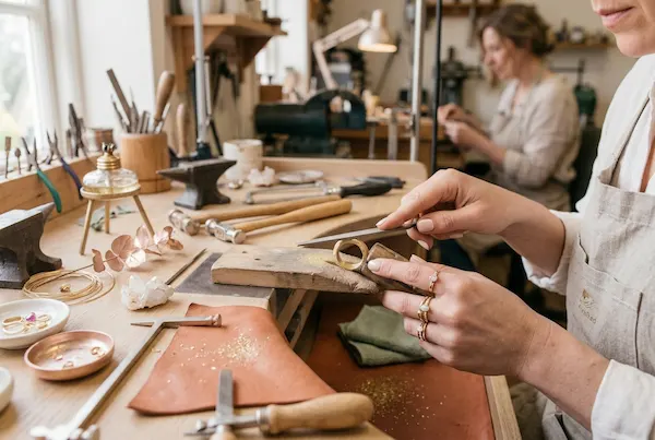 Artesana de joyería limando un anillo de oro en su taller.